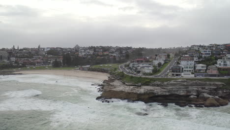 Aerial:-Drone-flying-over-the-ocean-on-an-overcast-cloudy-day-past-Tamarama-towards-Bronte,-near-Bondi-Sydney