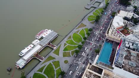 Aerial-flyover-of-rooftop-buildings-and-busy-crowded-traffic-riverside-road