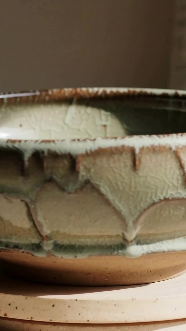 Video verticale: Telecamera in movimento che mostra una ciotola smaltata su un sottobicchiere chiaro, evidenziando le colature dello smalto.