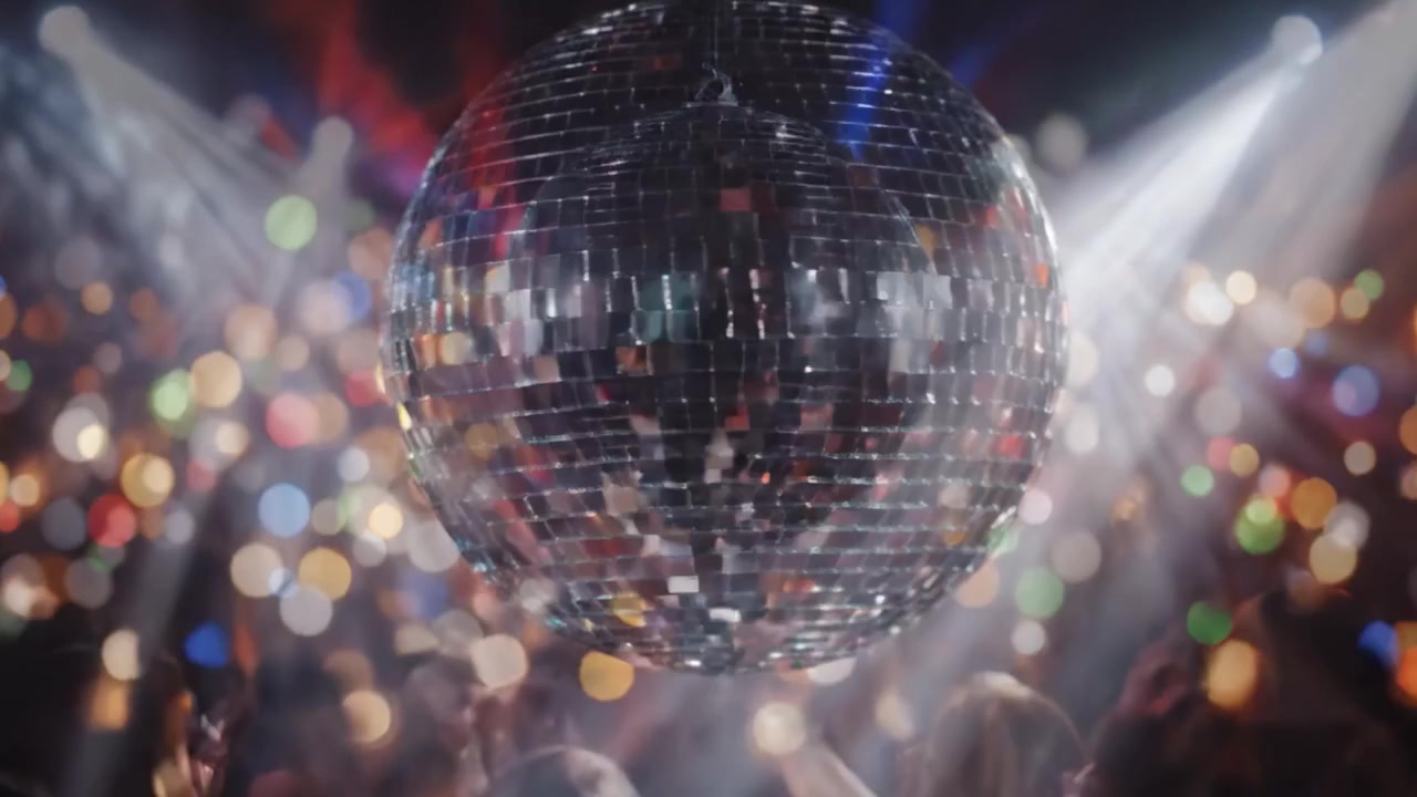 En gnistrende discokugle oplyser et pulserende dansegulv og fylder rummet med farverige lys og energiske stemninger ved en livlig fest