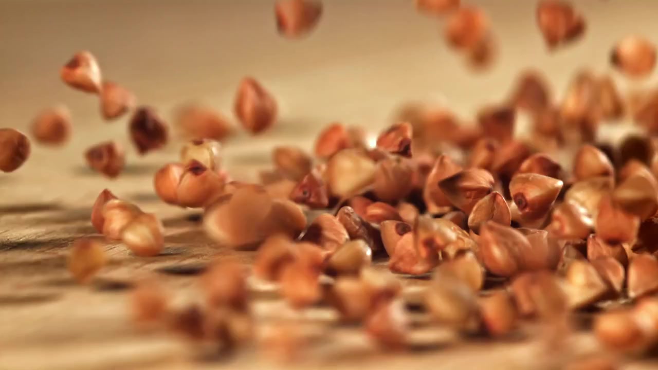 Grani di grano saraceno che cadono al rallentatore su una superficie di legno