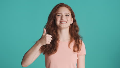 Redheaded-girl-looking-at-camera-on-turquoise-background.