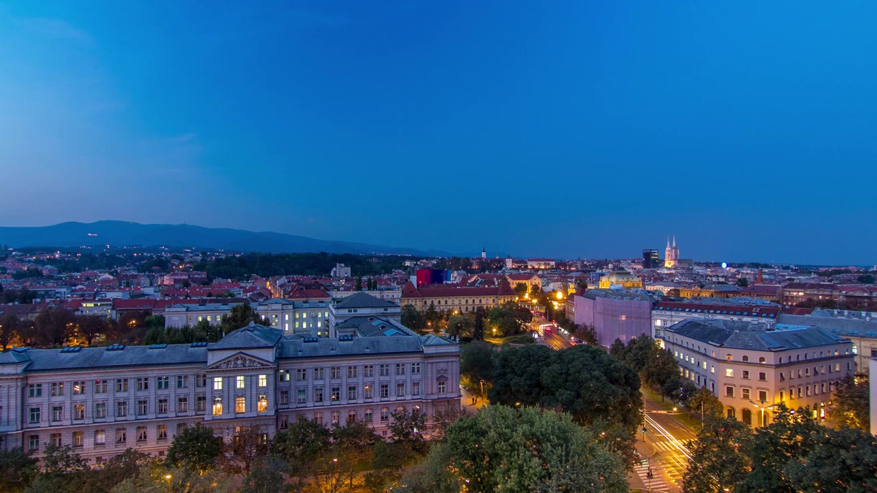 Panorama do centro da cidade timelapse filmado do topo do arranha-céu com vista para o cruzamento em frente ao teatro nacional e museu em Zagreb, Croácia. Vista antes do pôr do sol.
