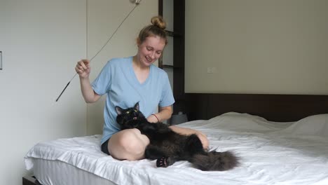 Black-Maine-Coon-cat-trying-to-catch-a-feather-as-owner-enjoys-the-fun