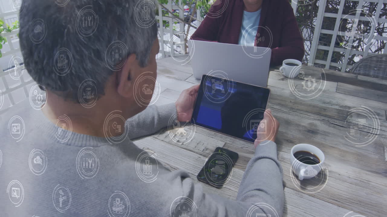 Business icons animation over people using tablet and laptop at outdoor cafe
