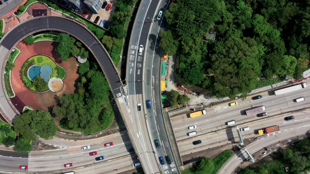 축소 회전 효과가 있는 홍콩의 붐비는 구룡 지구에 있는 철로가 있는 번화한 고속도로 교차로에서 교통의 하향식 보기