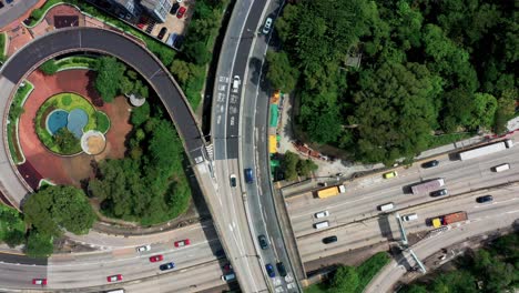 Top-down-view-of-a-traffic-in-a-busy-highway-intersection-with-railroad-tracks-in-the-crowded-Kowloon-district-in-Hong-Kong,-with-a-zoom-out-rotating-effect