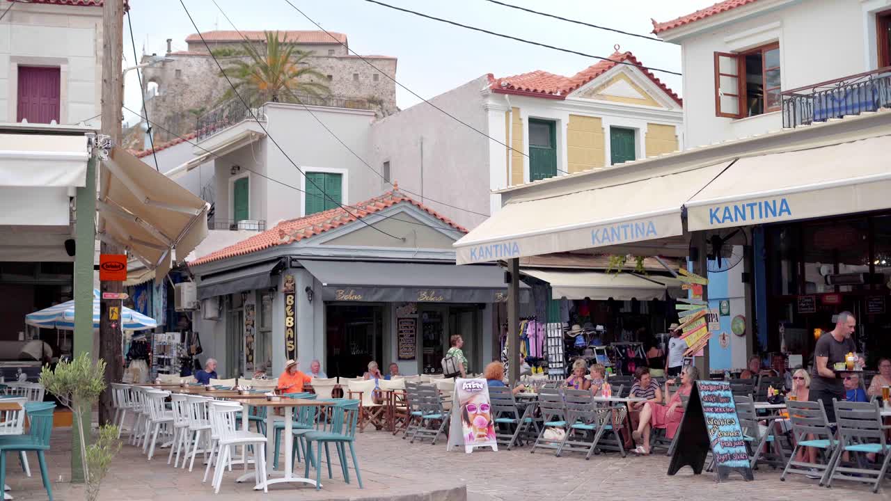 Traditional Greek taverna, cafe with outdoor seating in Petra cobblestone street with terracotta buildings in view, Gimbal shot