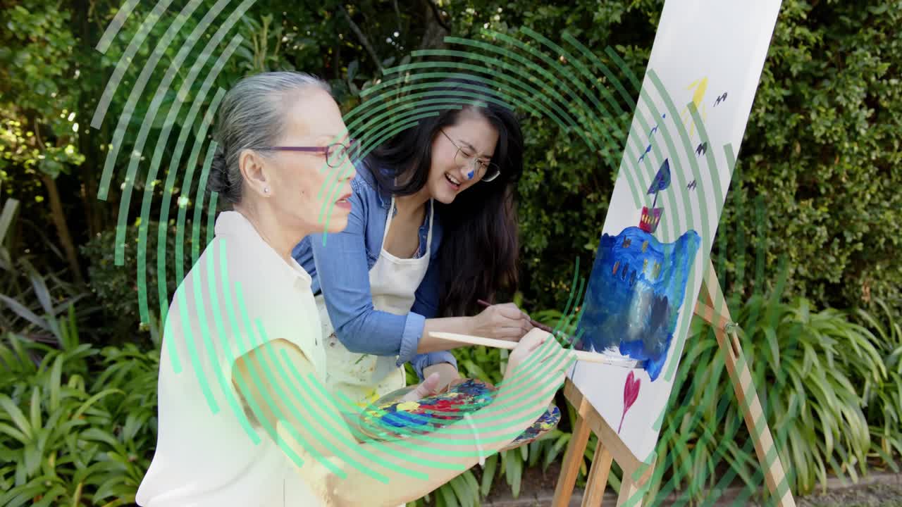 Senior guiding daughter, nudging her into painting seascape with palette, brush under green overlay