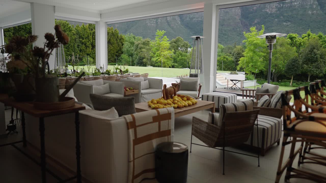 A beautiful setting in an undercover veranda of a luxury house showing expensive furniture and an exquisite view of a lush garden and large mountain