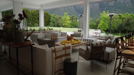 a beautiful setting in an undercover veranda of a luxury house showing expensive furniture and an exquisite view of a lush garden and large mountain