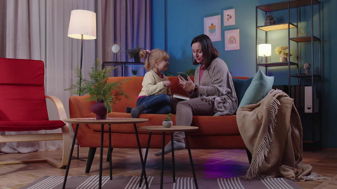 Child kid daughter showing to mother smartphone with good news message success win luck at home