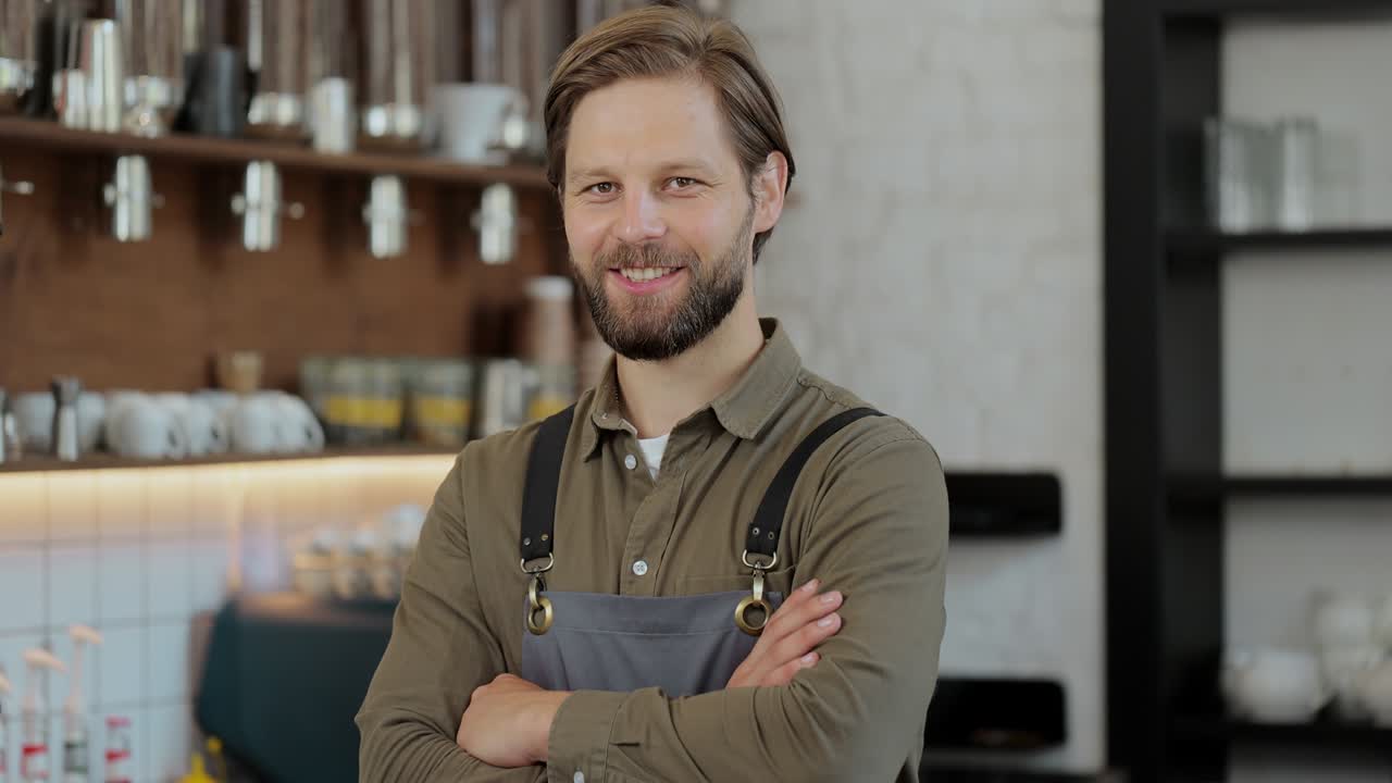 Successful small business owner man standing with crossed arms. Portrait of young male cafe owner. Coffee shop concept.
