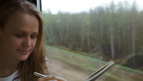 young woman making notes while traveling by train