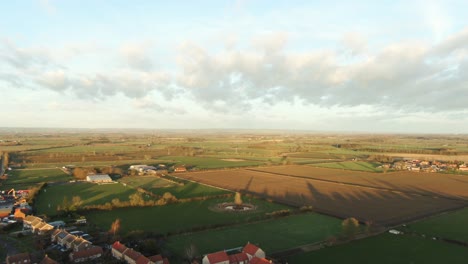 glowing sunset over the large flat fields of yorkshire in england growing crops surrounded by a small village