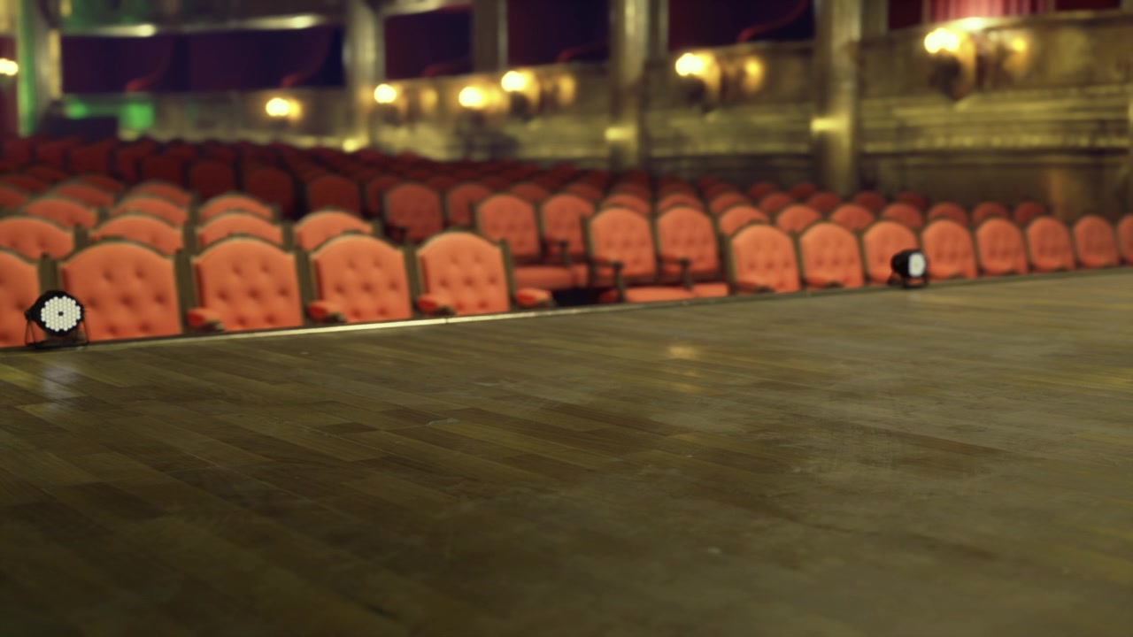 Warm lighting illuminates intimate performance setting with plush chairs