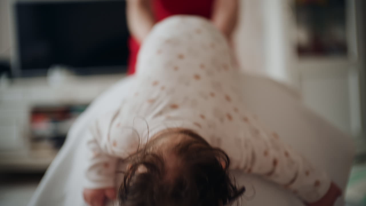 Baby placed on tummy on a stability ball while adults support the infant's torso and shoulders