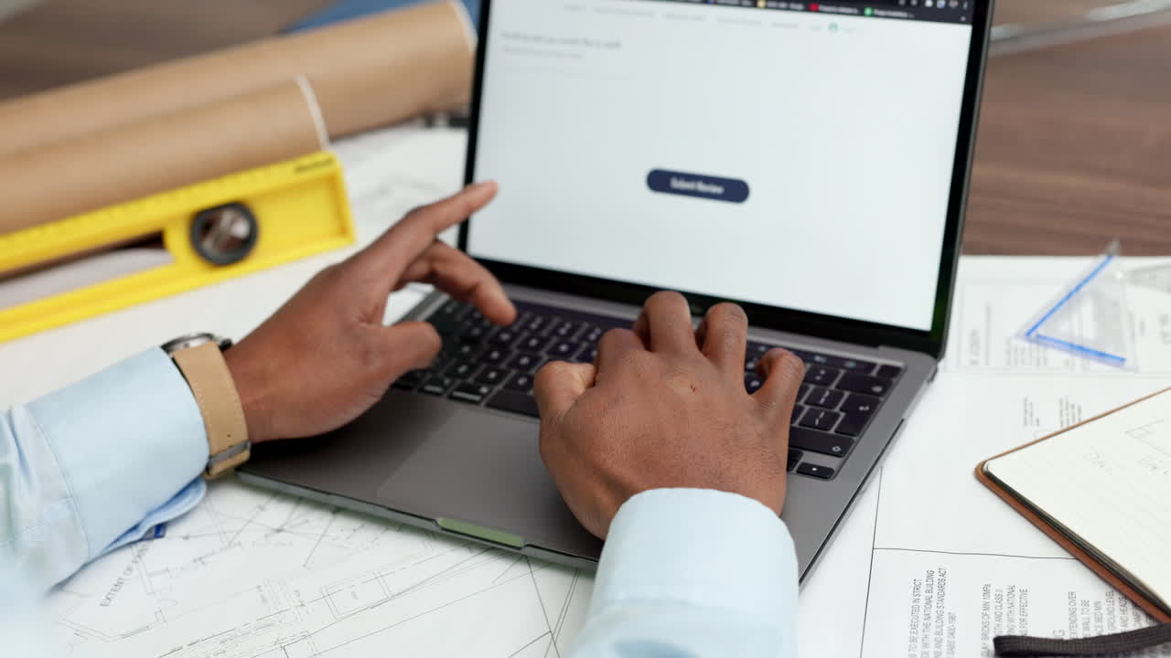 Person working on a laptop with architectural plans
