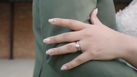 bride rubbing hand up grooms arm sleeve showing ring in 4k slow motion