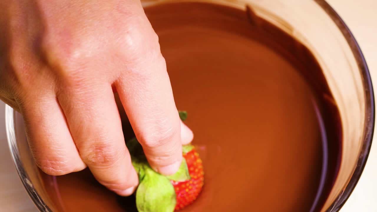 손으로 녹은 초콜릿에 담긴 딸기