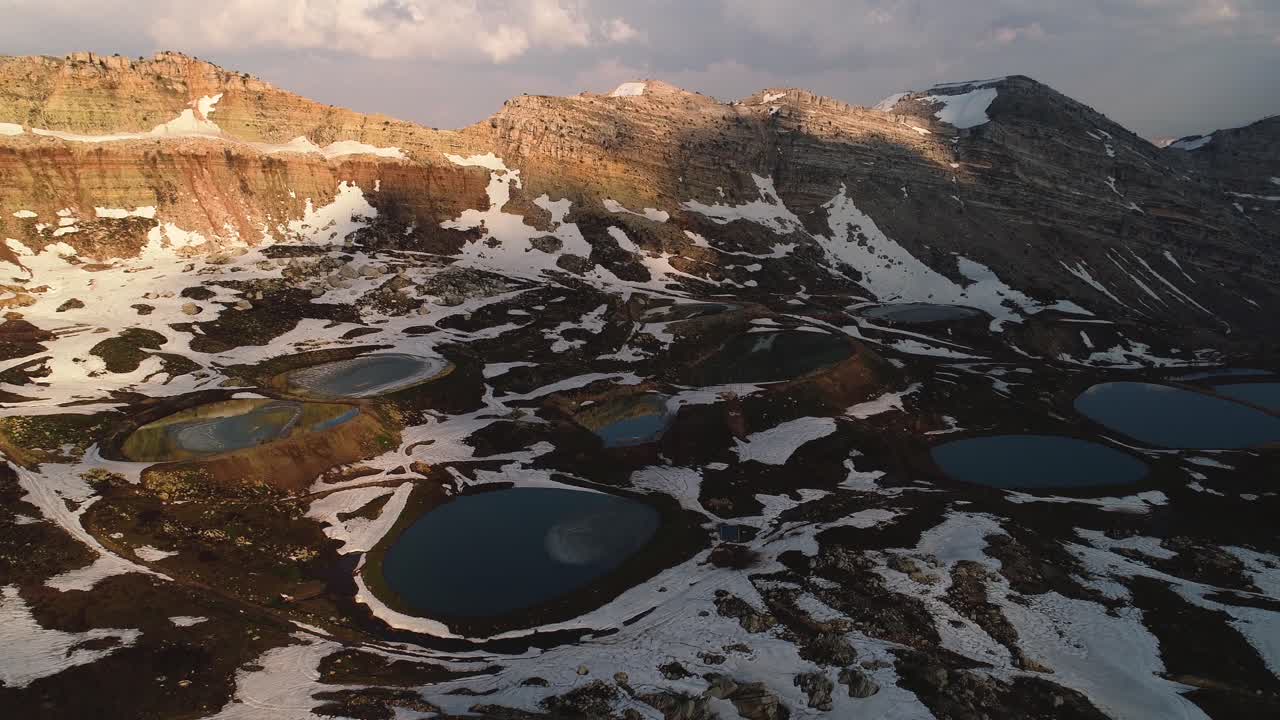 High aerial rising and tilt down shot of snowy Akoura lakes at sunset, Mont-Liban, Lebanon