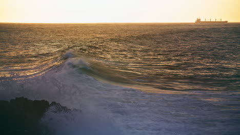 Calm-sea-waves-rolling-to-rocky-coastline.-Lonely-ship-silhouette-at-horizon.