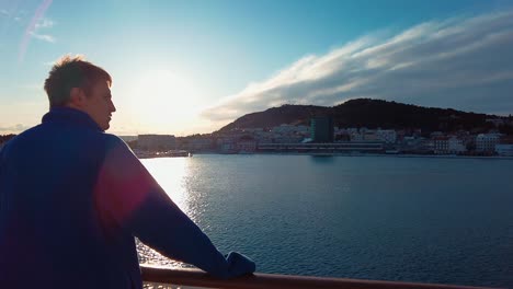 back view of a tourist with brown hair and a blue jacket sightseeing during the corona pandemic. view of sailing ferry boat from the split island to island vis in croatia, in the adriatic sea. 4k uhd