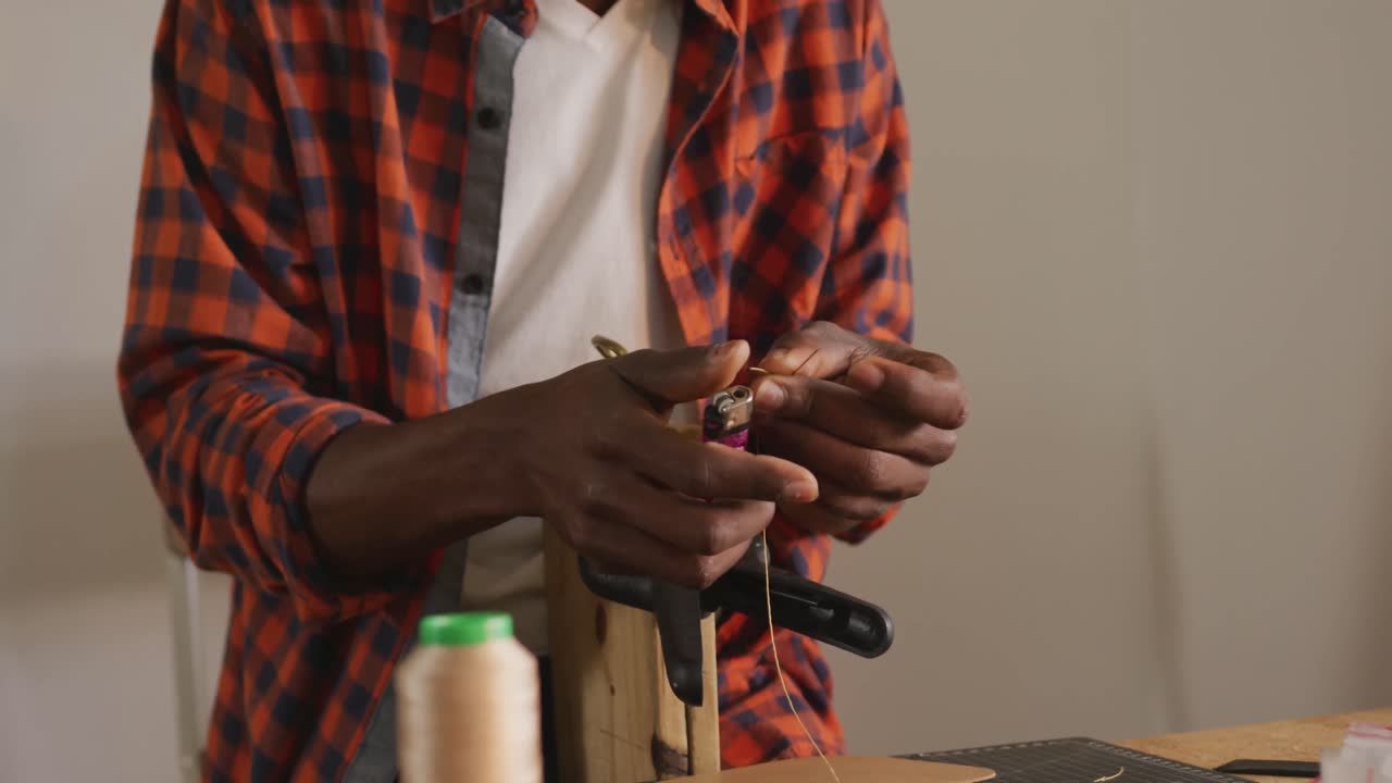 sección media de un artesano afroamericano preparando un cinturón en un taller de cuero
