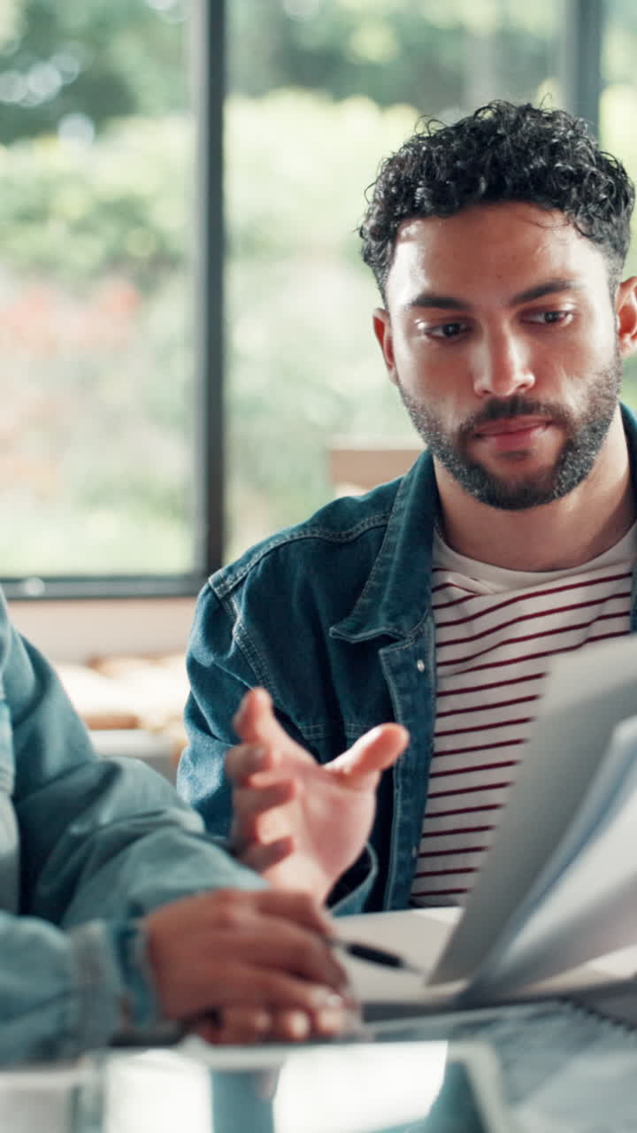 Young Man Discussing Documents and Gesturing During a Meeting