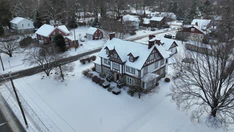 tudor-style home in a snow-covered neighborhood, bare trees, winter day