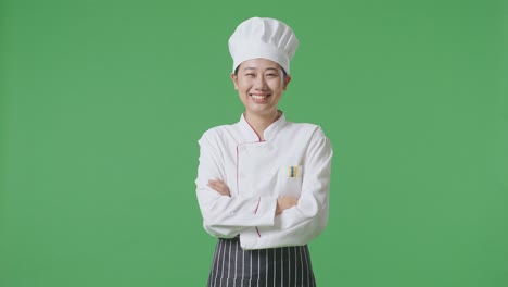 Asian Woman Chef Smiling And Crossing Her Arms To Camera While Standing In The Green Screen Background Studio