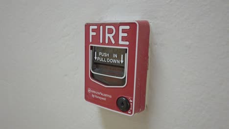 Medium shot of red and white fire alarm on a wall inside a building, indoor