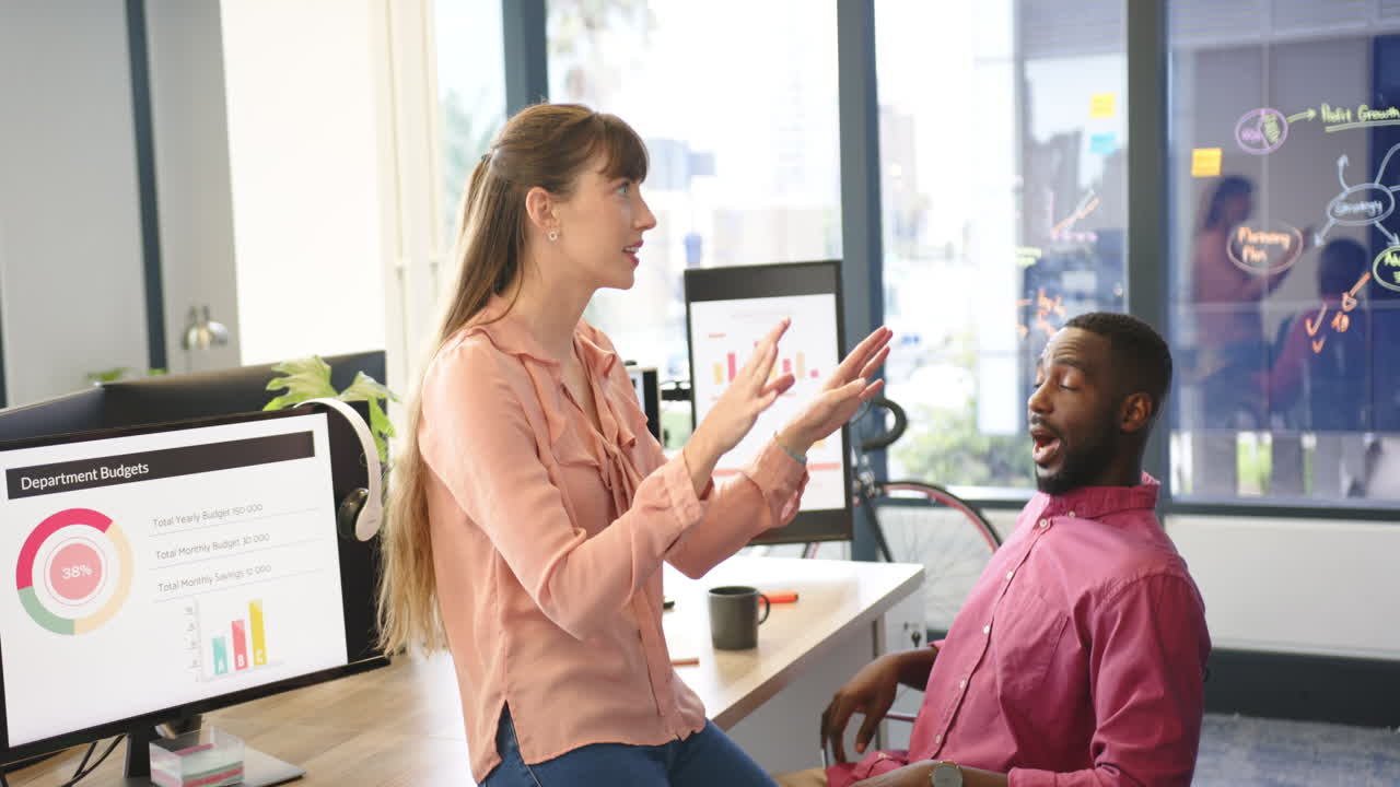 Discussing project, diverse colleagues analyzing charts on computer screens in modern office
