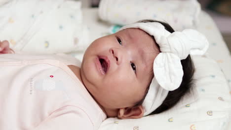 estirando sus piernas y brazos mientras se mueve de un lado a otro, un bebé recién nacido también le está frotando los ojos y mostrando una pequeña sonrisa en su rostro gordo