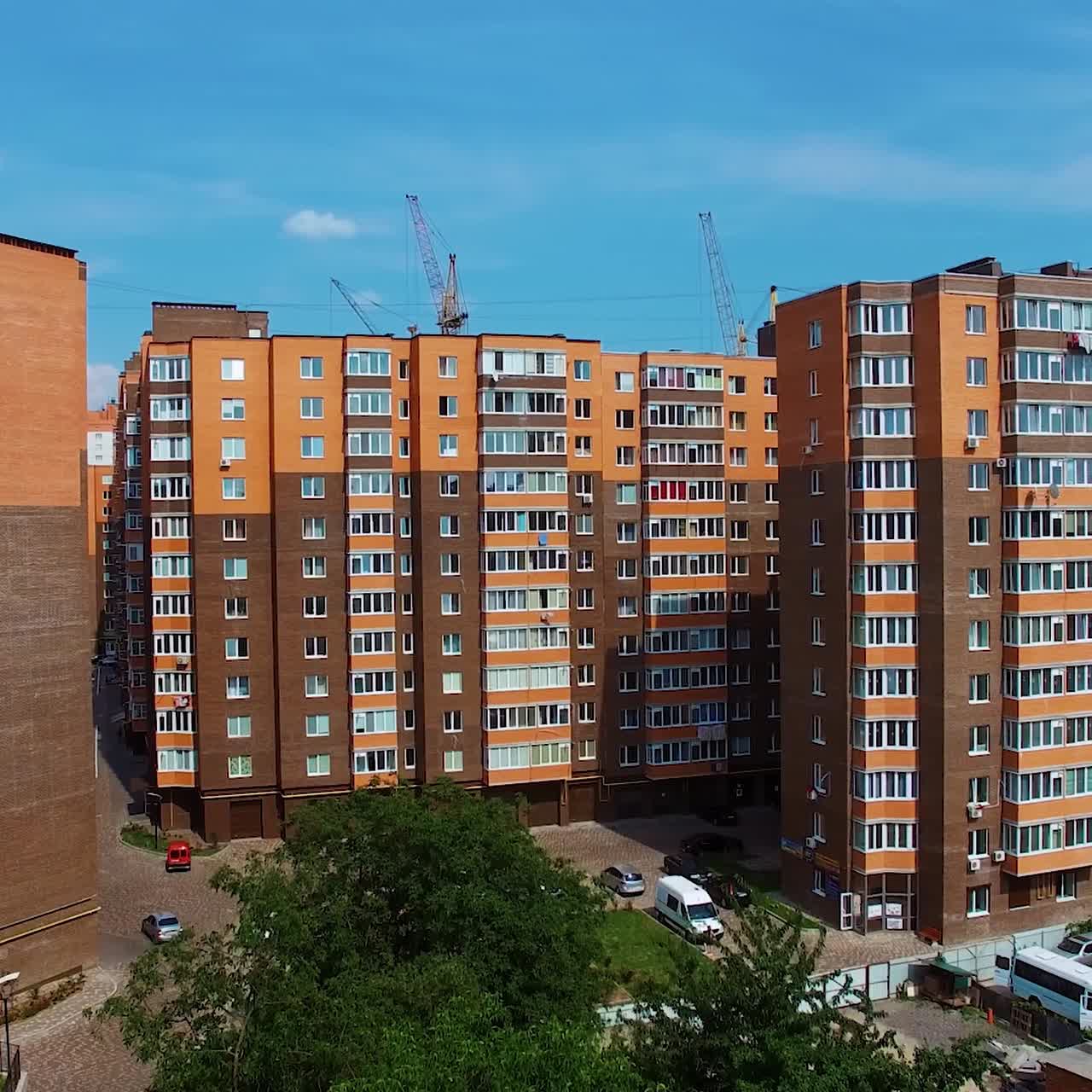 New high buildings in the city. Residential apartments under the blue sky. Architecture in brown colors in the modern district. Camera rising up.