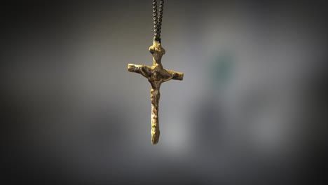 High-quality-close-up-render-of-a-beautiful-antique-gold-Christian-Crucifix-artifact-swinging-slowly-on-the-end-of-a-neck-chain,-with-super-shallow-depth-of-field-abd-bokeh-background