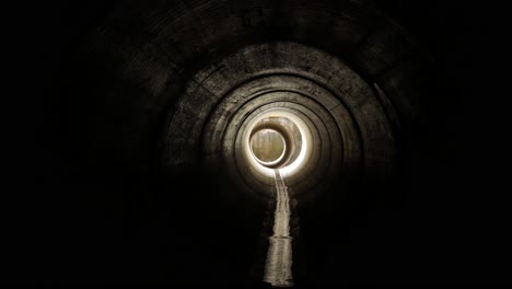 a clip walking towards the light inside a big pipe