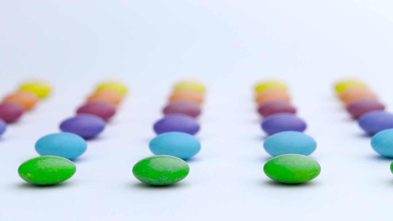 las filas de dulces redondas coloridas se mueven horizontalmente sobre el fondo blanco.