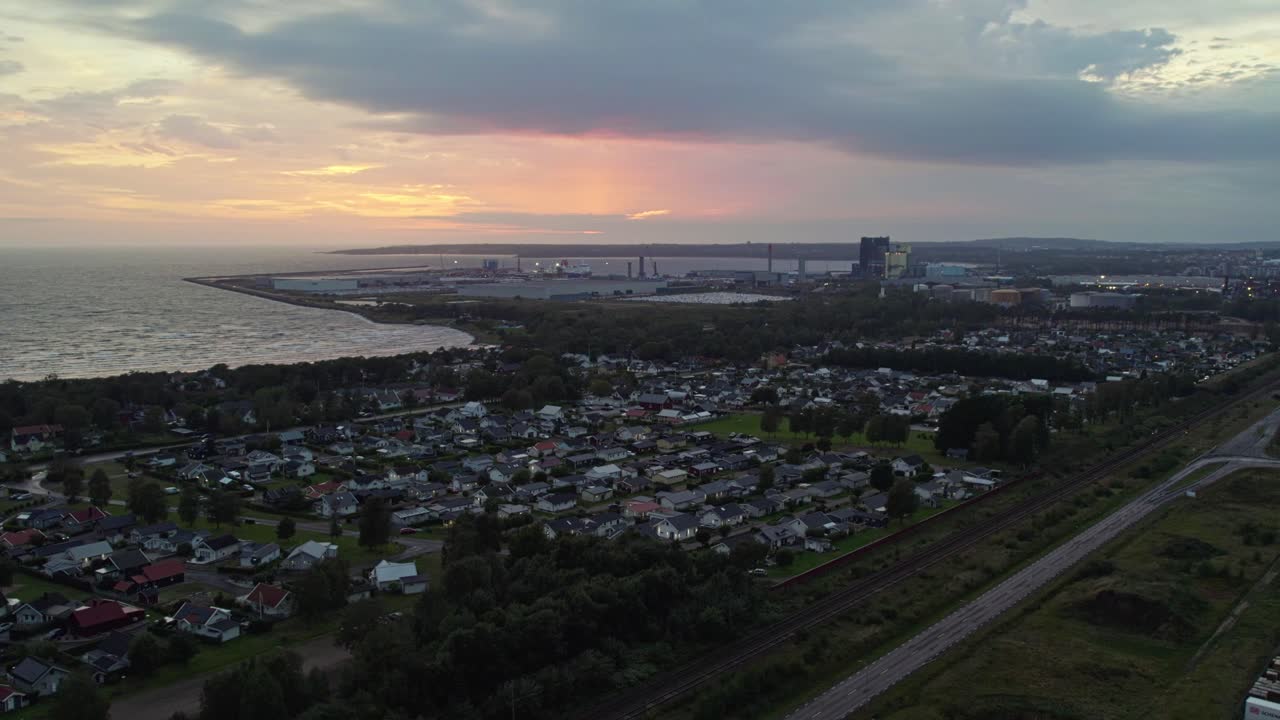Birds eye aerial view of Östra Stranden, Halmstad’s iconic long sandy beach with shallow turquoise water and adjacent modern residential neighbourhood, captured during golden hour