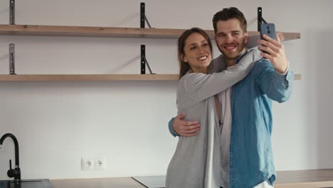 una pareja caucásica muy emocionada haciendo una videollamada en su nuevo apartamento.