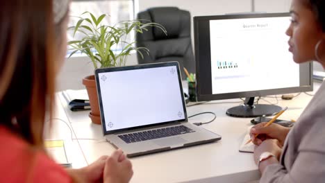 mujeres de negocios diversas hablando y usando computadora portátil con pantalla en blanco
