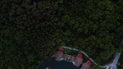 Beautiful-top-bird's-eye-aerial-drone-shot-of-a-group-of-bungalows-along-a-small-river-surrounded-by-a-mangrove-forest-in-a-tropical-vacation-resort-in-Riviera-Maya,-Mexico-near-Mexico