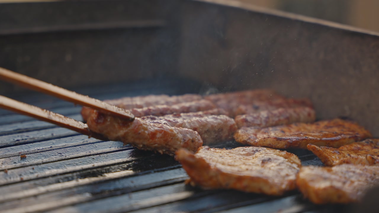 Hands turning grilled meat on barbecue, casual outdoor cooking scene in garden