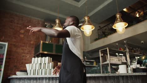 Close-up-shot-of-a-Black-person-in-a-doner-market-dancing-with-wireless-headphones.-Cool-dance-at-work-in-honor-of-success