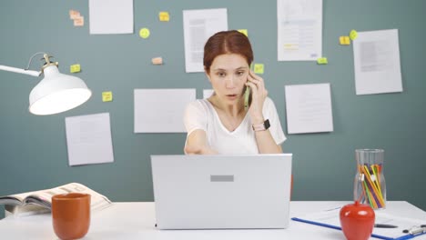 Woman-using-laptop-nervously-talking-on-the-phone.