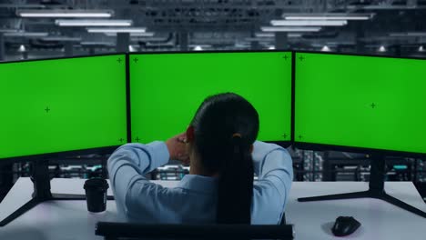 back view of tired asian woman stretching while working with mock up multiple computer monitor in data center