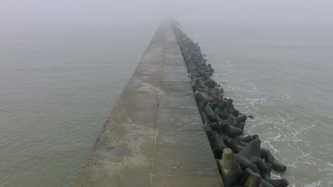리파자 콘크리트 부두 항구, 발트해 해안선, 짙은 안개가 낀 안개 낀 날, 변덕스러운 느낌, 큰 폭풍우가 튀는 것, 버드아이 드론 샷이 앞으로 낮게 움직이는 모습