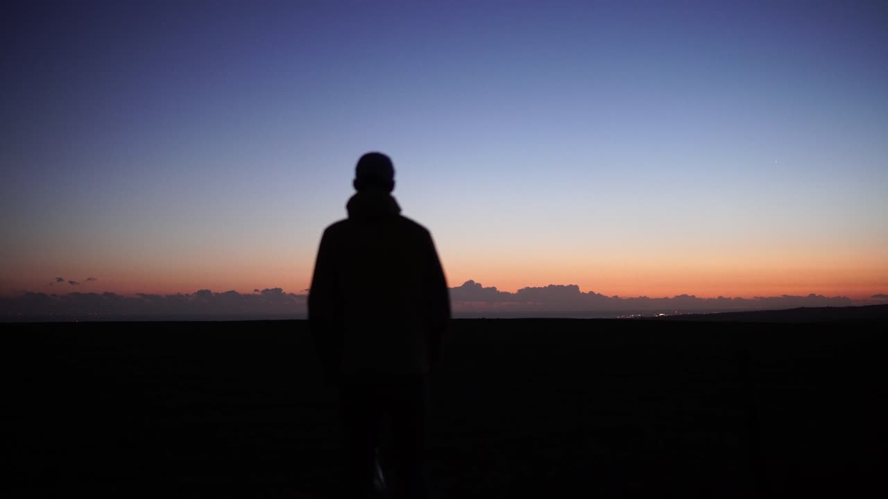 오렌지색 해가 지는 것을 바라보는 남자의 실루