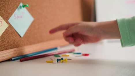 child hand touches colorful pins and takes pin with red flag