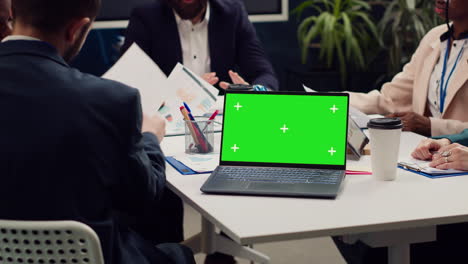 business partners attending meeting next to greenscreen laptop